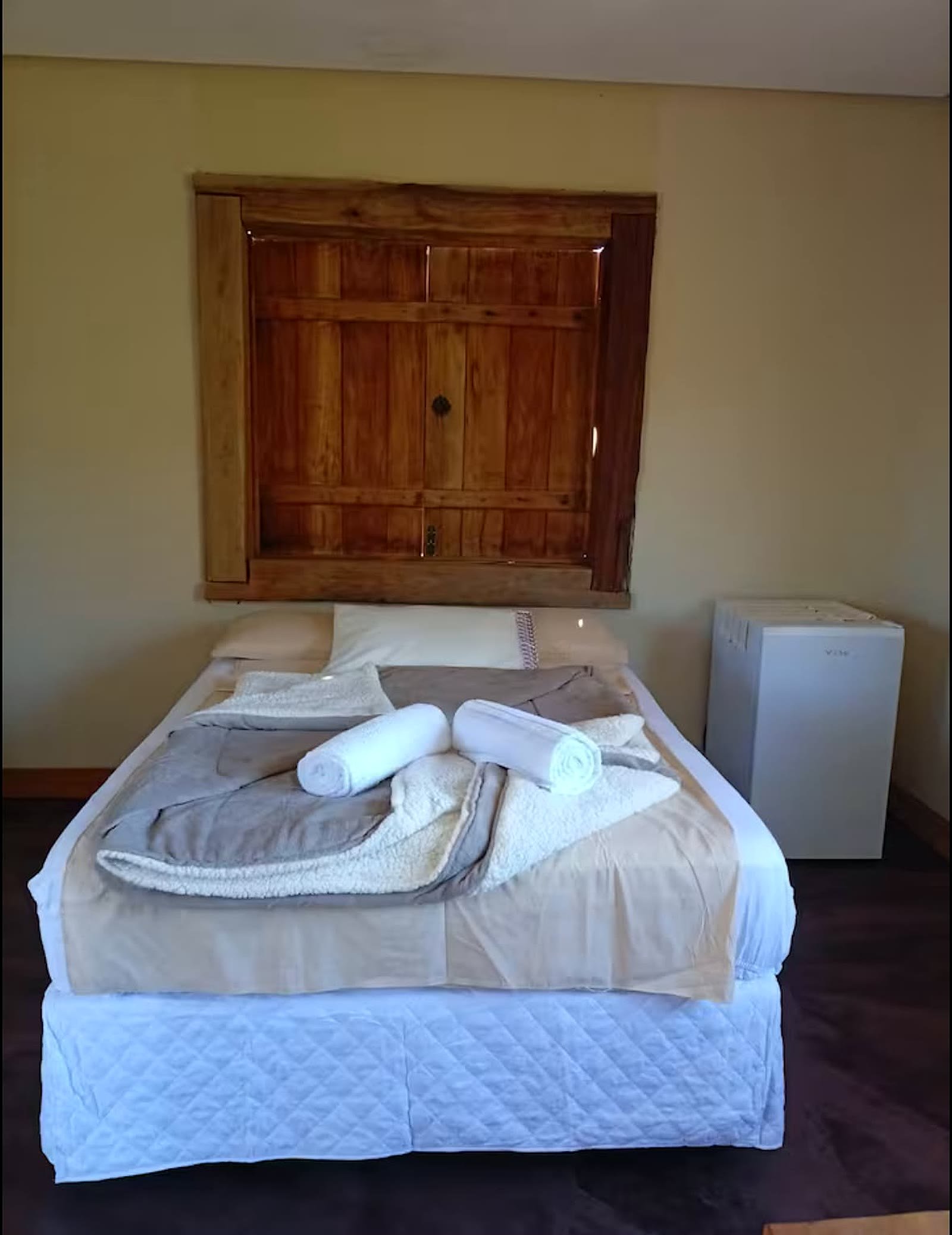 Cama de casal do chalé 3 com janela rústica de madeira